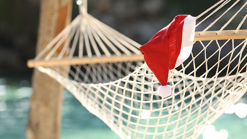Weihnachtsmütze liegt auf Hängematte an einem tropischen Strand